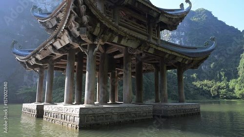 Traditional vietnamese temple standing on water with karst mountains in background in Ninh Binh province