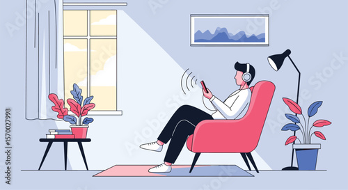 Relaxed young man listening to music on headphones while sitting in a comfortable armchair with a tablet in a bright living room near a window