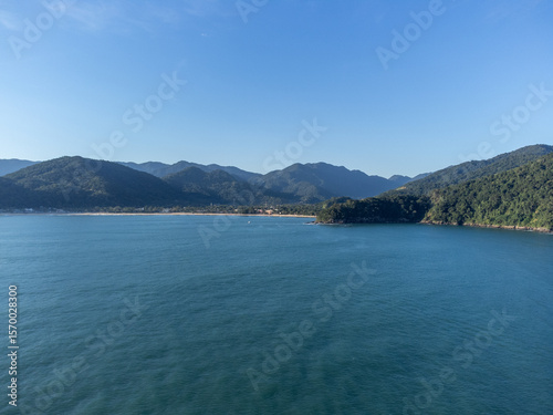 Setting sun on beautiful tropical beach amidst forested mountains