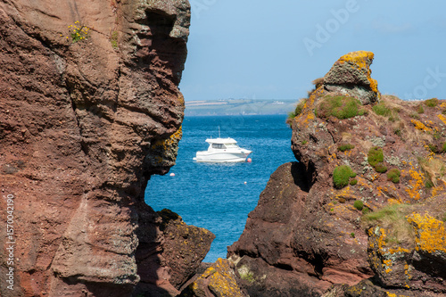 Fototapeta Naklejka Na Ścianę i Meble -  Motorboat Framed by Red Cliffs on the Irish Coast of Dunmore East