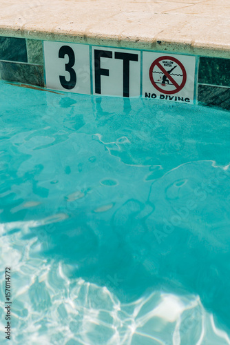 Pool area showing a clear depth indicator with a no diving sign during daylight hours