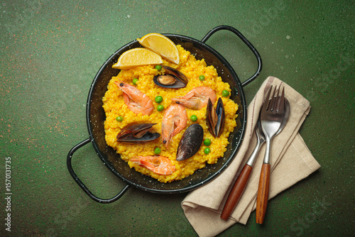 Photography Seafood paella with rice, shrimp, mussels, peas, and lemon wedges served in a bl