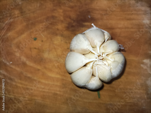 Fototapeta Naklejka Na Ścianę i Meble -  Top view of some raw garlic cloves or Bawang Putih (Indonesian), isolated on a wooden cutting board with empty space.