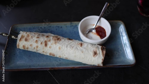 Juicy lula kebab wrapped in grilled lavash served on a ceramic plate with creamy and spicy sauces capturing the rich flavor and aroma of traditional Caucasian cuisine