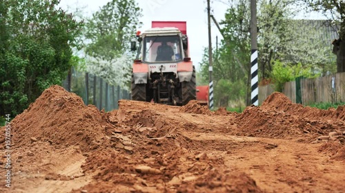 Tractor preparing ground for road construction in slavic village