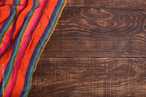 Colorful typical mexican tablecloth on wooden table. Background, texture.