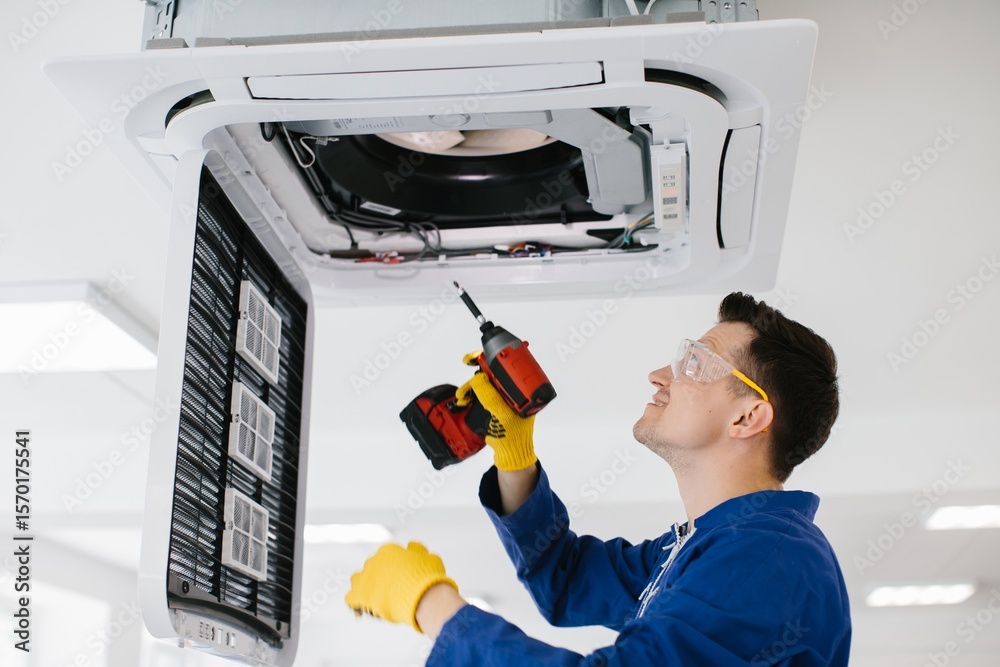Fototapeta premium Technician repairing air conditioner using electric screwdriver