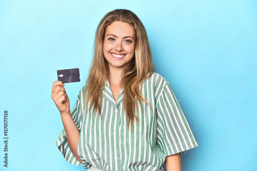 Young blonde with a credit card in blue studio happy, smiling and cheerful. Young blonde with a credit card in blue studio happy, smiling and cheerful.