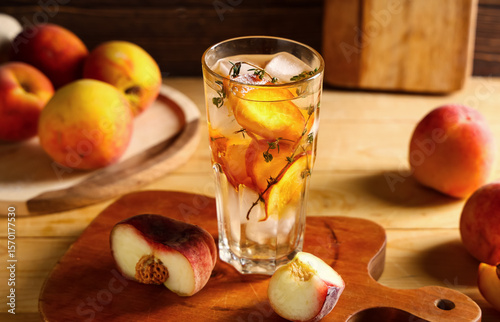 Fototapeta Naklejka Na Ścianę i Meble -  Glass of fresh peach lemonade with thyme and fruits on wooden background