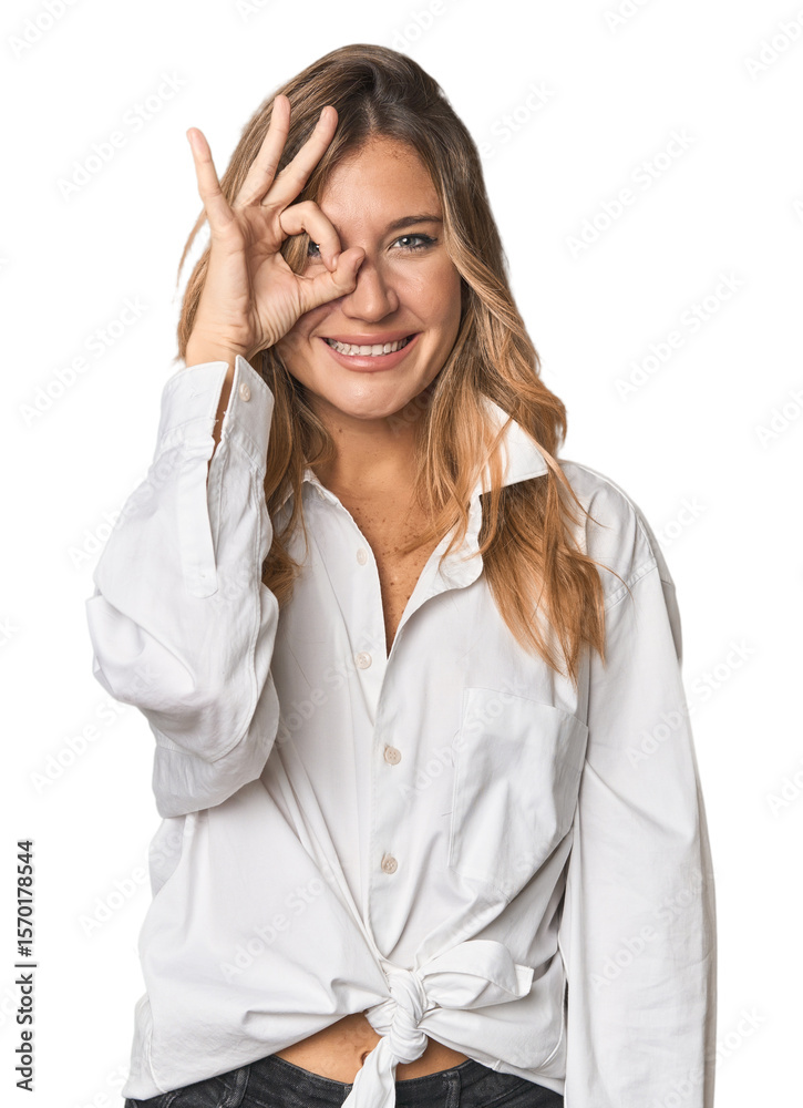 Caucasian blonde woman in studio excited keeping ok gesture on eye. Caucasian blonde woman in studio excited keeping ok gesture on eye.