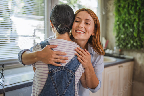 Fotografie female friends hug each other in the kitchen at home