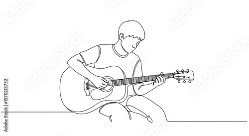 Young boy playing acoustic guitar while sitting on the floor  