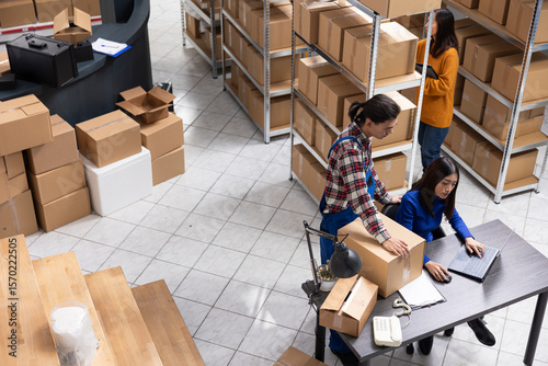 Local brand supply room staff work at distribution hub for order processing and hand packing merchandise. Ensuring local shipping and in house logistics operations for retail fulfillment.