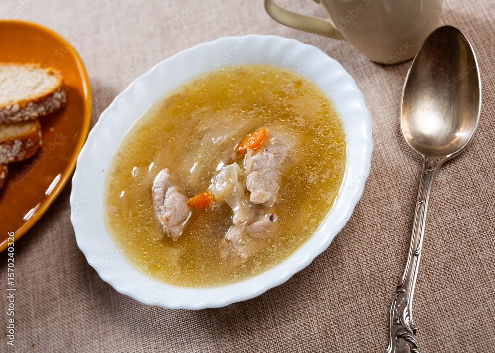 On wooden table there are plate is filled to brim with fresh cabbage soup from selected vegetables and juicy pork ribs.. On wooden table there are plate is filled to brim with fresh cabbage soup from selected vegetables and juicy pork ribs..