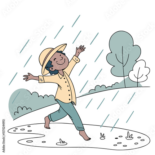 Joyful child wearing a hat and yellow shirt runs barefoot through puddles and rain with arms outstretched in a park