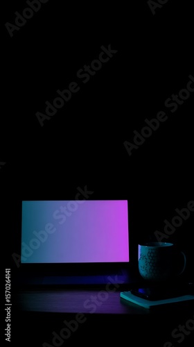 Laptop and mug on a wooden surface in low light.