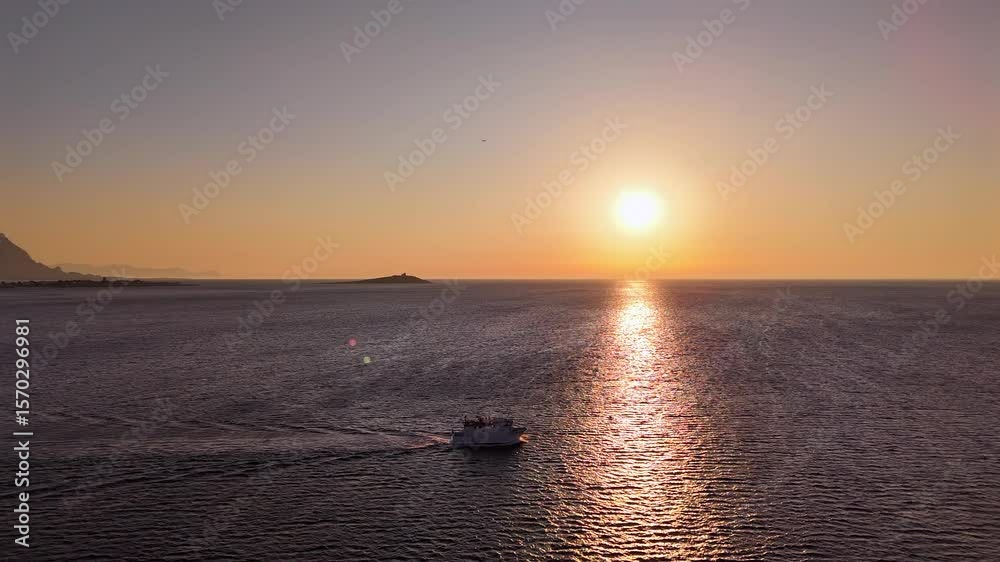 Peschereccio in navigazione nel golfo di sferracavallo accarezzato dal sole al tramonto durante una battuta di pesca estiva al gambero rosso di mazzara del vallo vista dall'alto con drone