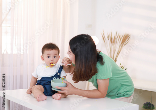 Fotografie The mother who is feeding her little boy on the table wants to be happy