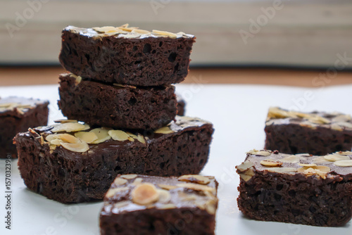 Homemade Stacked Chocolate Brownies cake with topping almond slice on white background. side view