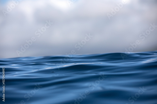 Fototapeta Naklejka Na Ścianę i Meble -  Close-up sea level view of blue rippling ocean's surface under a stormy cloud-filled sky.