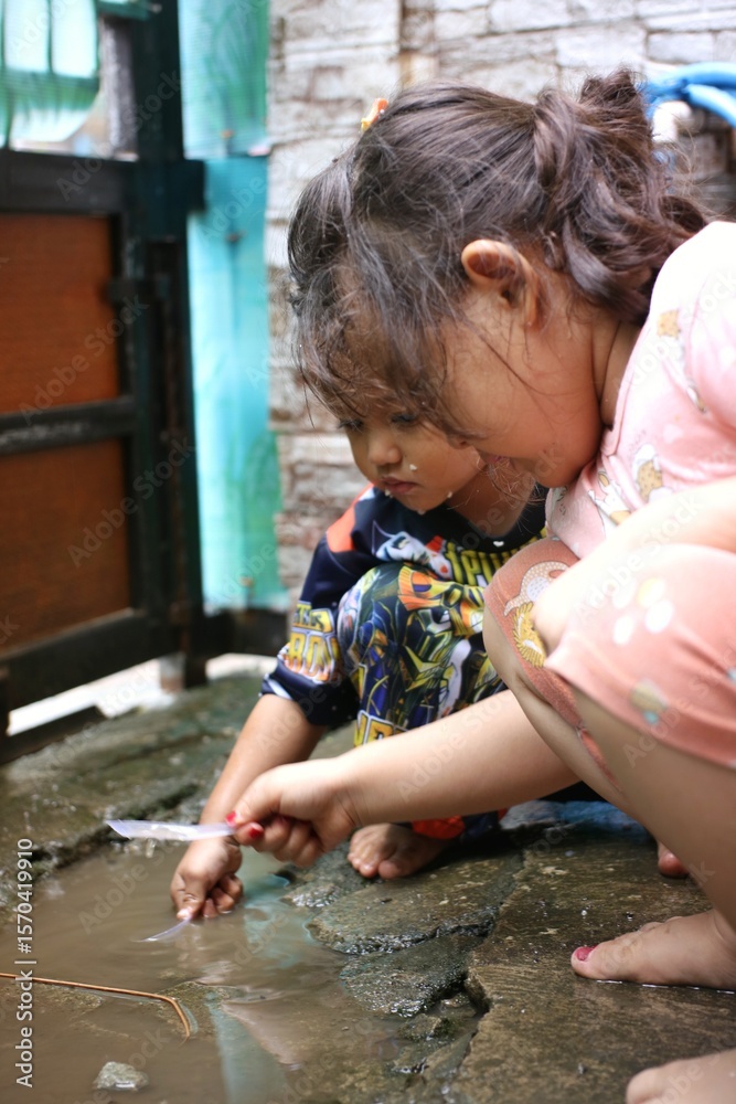 Fototapeta premium Two Little Children Playing Outdoors in a Watery Yard