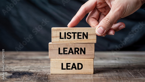Hand stacking wooden blocks with the words listen learn lead symbolizing personal growth and leadership development journey