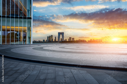 Empty square floor and modern office building with city skyline scenery at sunset in Suzhou, China.