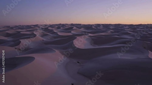 Desert landscape with sand dunes creating ripples shadow lines at dusk