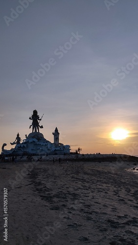 Majestic Statue Silhouetted Against a Golden Beach Sunset
