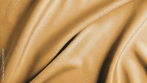 Golden, soft silk satin fabric with a smooth, shiny texture creates a luxurious and elegant golden textile background pattern