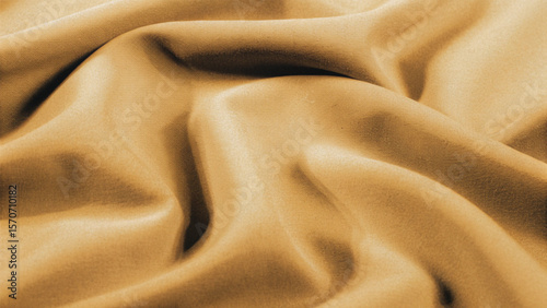 Golden, soft silk satin fabric with a smooth, shiny texture creates a luxurious and elegant golden textile background pattern