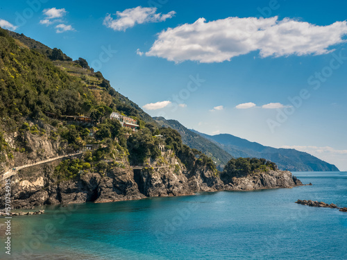The coast with crystal clear water and green terraces on the slopes. A calm b...