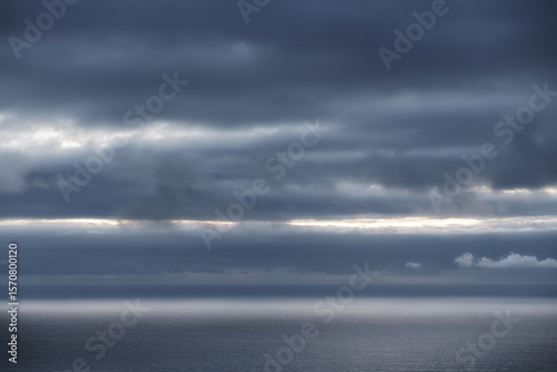 Moody cloudy sky over a dark ocean horizon with a band of light