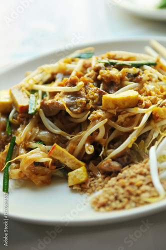 A close up photo of famous street food in Thailand, Pad Thai. It  s a noodle stir fry with a sweet-savoury-sour sauce scattered with crushed peanuts .