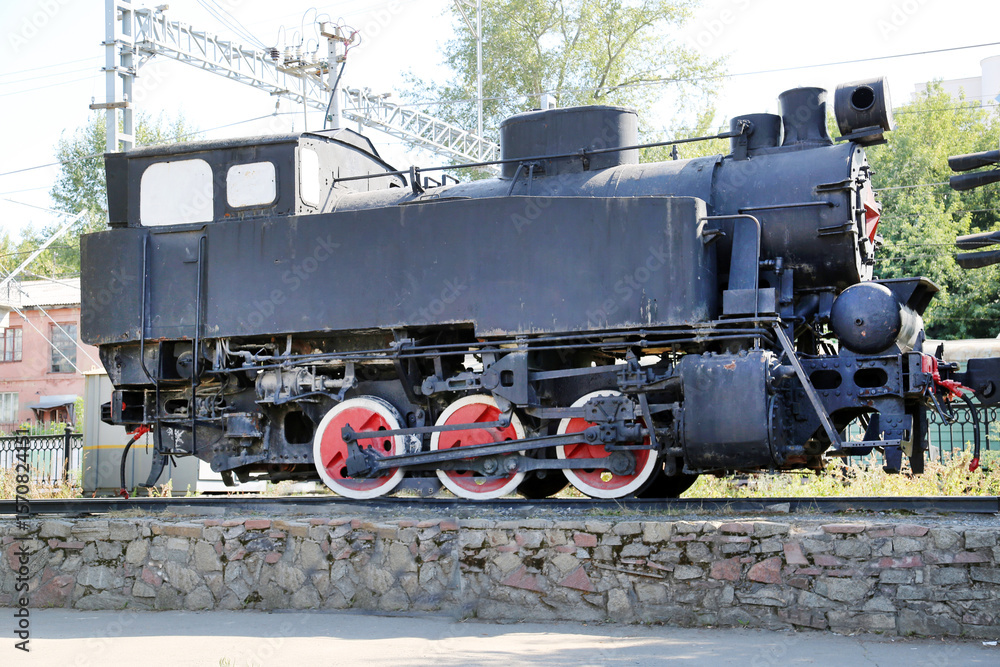 Naklejka premium An old blue steam locomotive of small size standing on rails on a clear sunny day, USSR. Transport, railway, machinery.