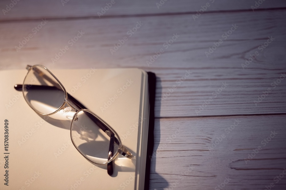 Fototapeta premium Golden eyeglasses kept on blank book at desk