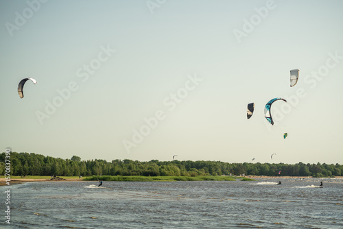 Seaside beach hosts kite surfing with sails flying in summer season. Water sport event, tourist travel hotspot, physical activity joy, summer extreme entertainment, competitive outdoor recreation