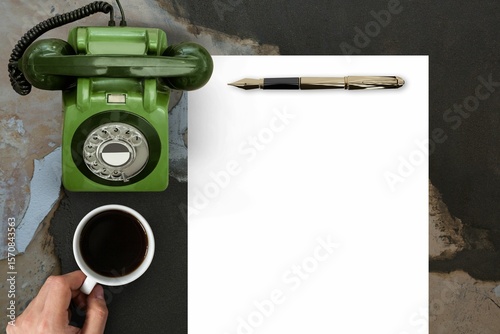 Man drinking coffee in front of paper and phone