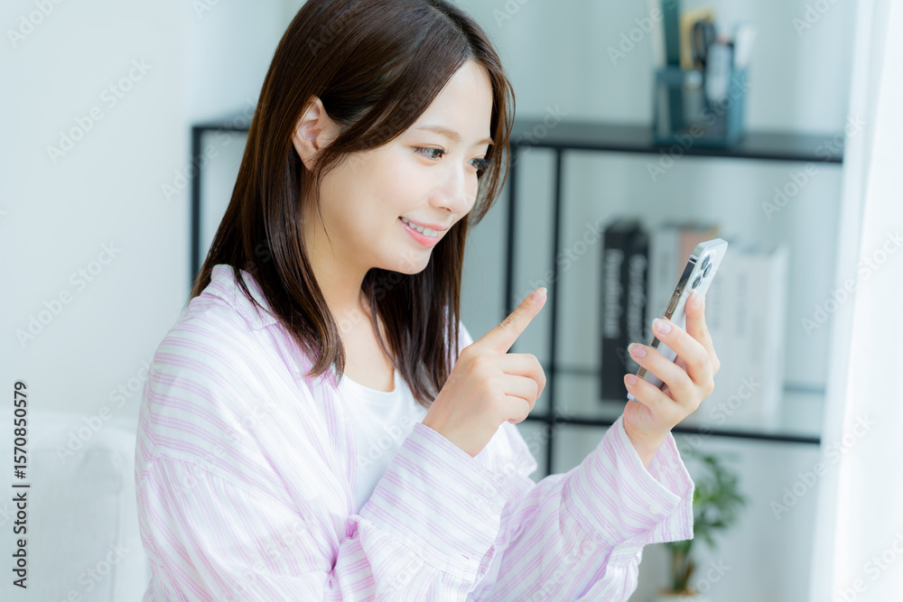 部屋でスマホを操作する若い女性 部屋でスマホを操作する若い女性