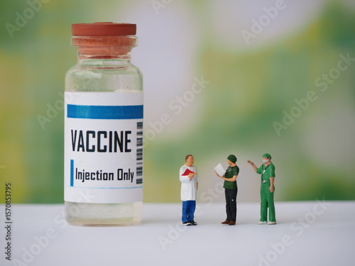 Mini toy of action figure with blurred background. Miniature photography concept design. Minifigure of healthcare crew with vaccine bottle.