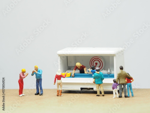 Mini toy of action figure at table with blurred background. Business photography concept design. Minifigure people character eating food at outdoor cafe with foodtruck.