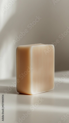 Simple natural soap block on a clean surface with soft shadows in gentle light during daytime