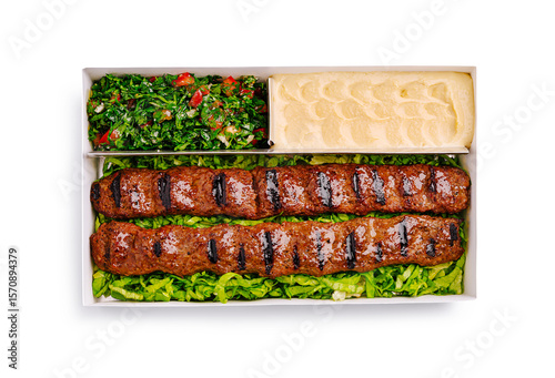 Grilled kebabs served with fresh salad and creamy dip in takeout box