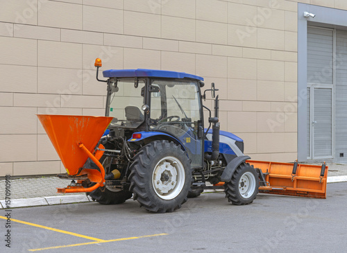 Tablou pe pânză Tailgate Salt Spreader Orange Hopper and Snowplow at Blue Tractor Cleaning Parki