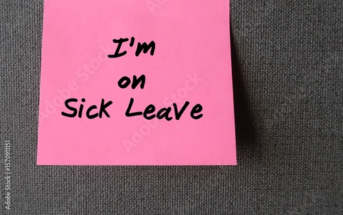 Office wall with stick note written I'M ON SICK LEAVE -  Employee takes time away from work of illness -note worker left to inform he is absent from job due to an illness, injury or accident