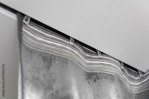 Close-up of the silver curtain hanging from the ceiling rail in the bathroom, creating a stylish and modern atmosphere.