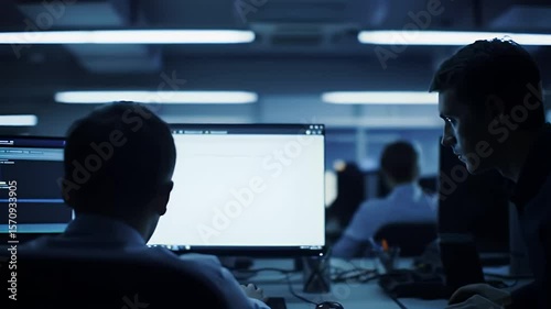 Young Man in Navy Shirt Using Computer At Desk in Dark Office with Blue Neon Lights During Night Time
