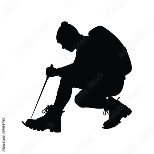 Silhouette of hiker attaching crampons to boots winter