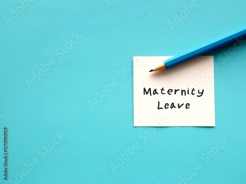 On blue copy space background - Pencil wrote on note Maternity Leave - period in which female employees allowed to absent from work before and after she gives birth - to take care of newborn child