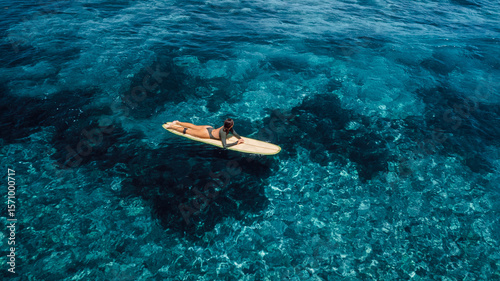 Photography Woman swim on surfboard in blue ocean